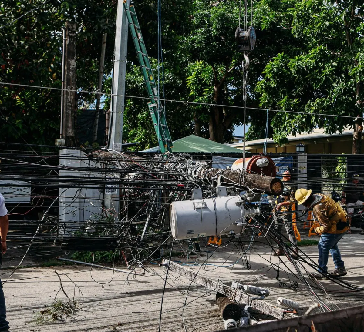 Workers repairing tangled utility cables outdoors.