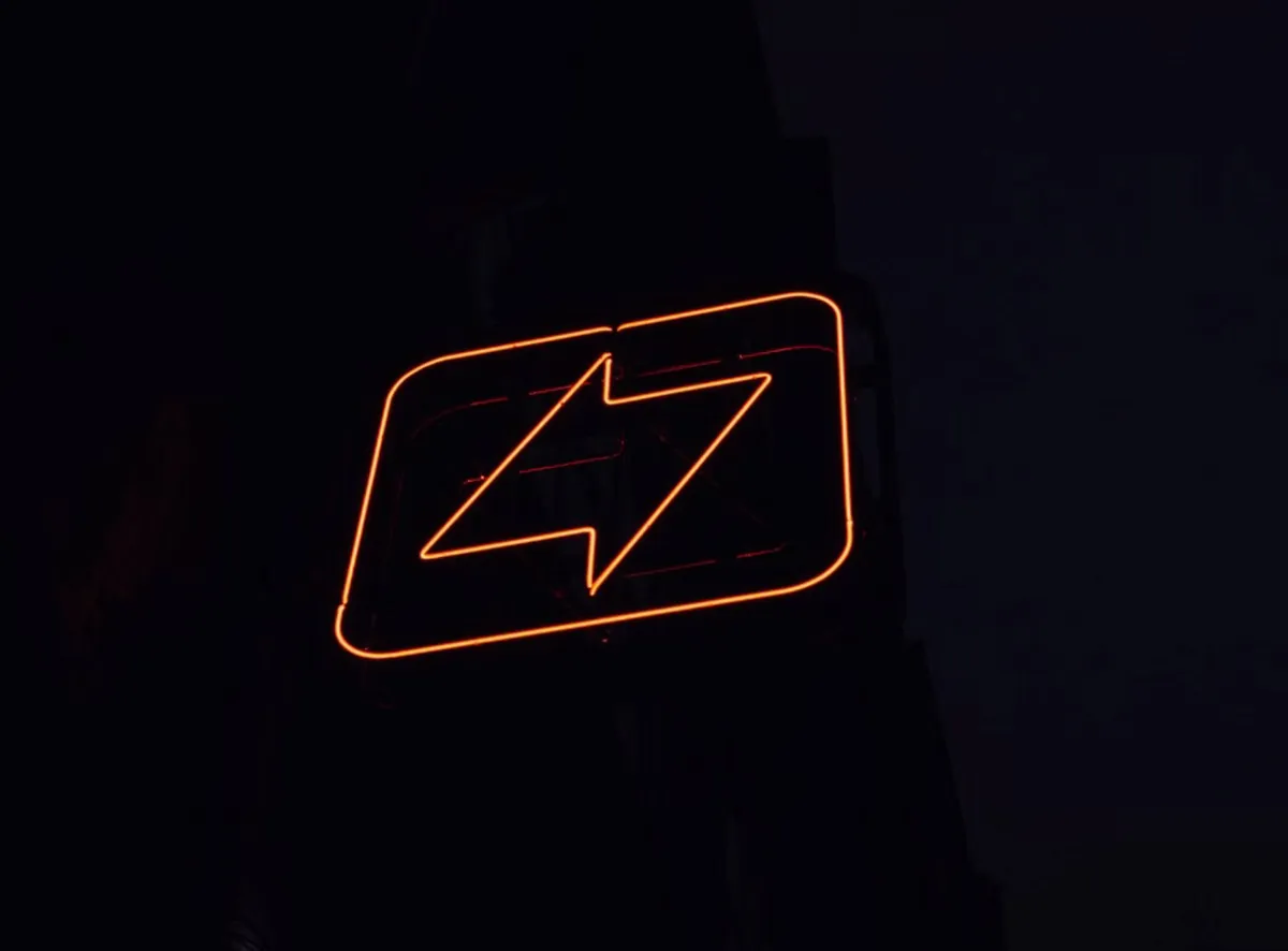 Neon lightning bolt sign in darkness.