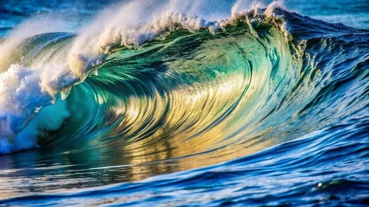 Large ocean wave with sunlight reflections.
